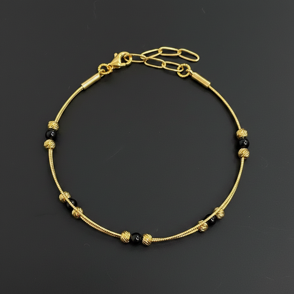 Gold bracelet with black beads on a red textured fabric background