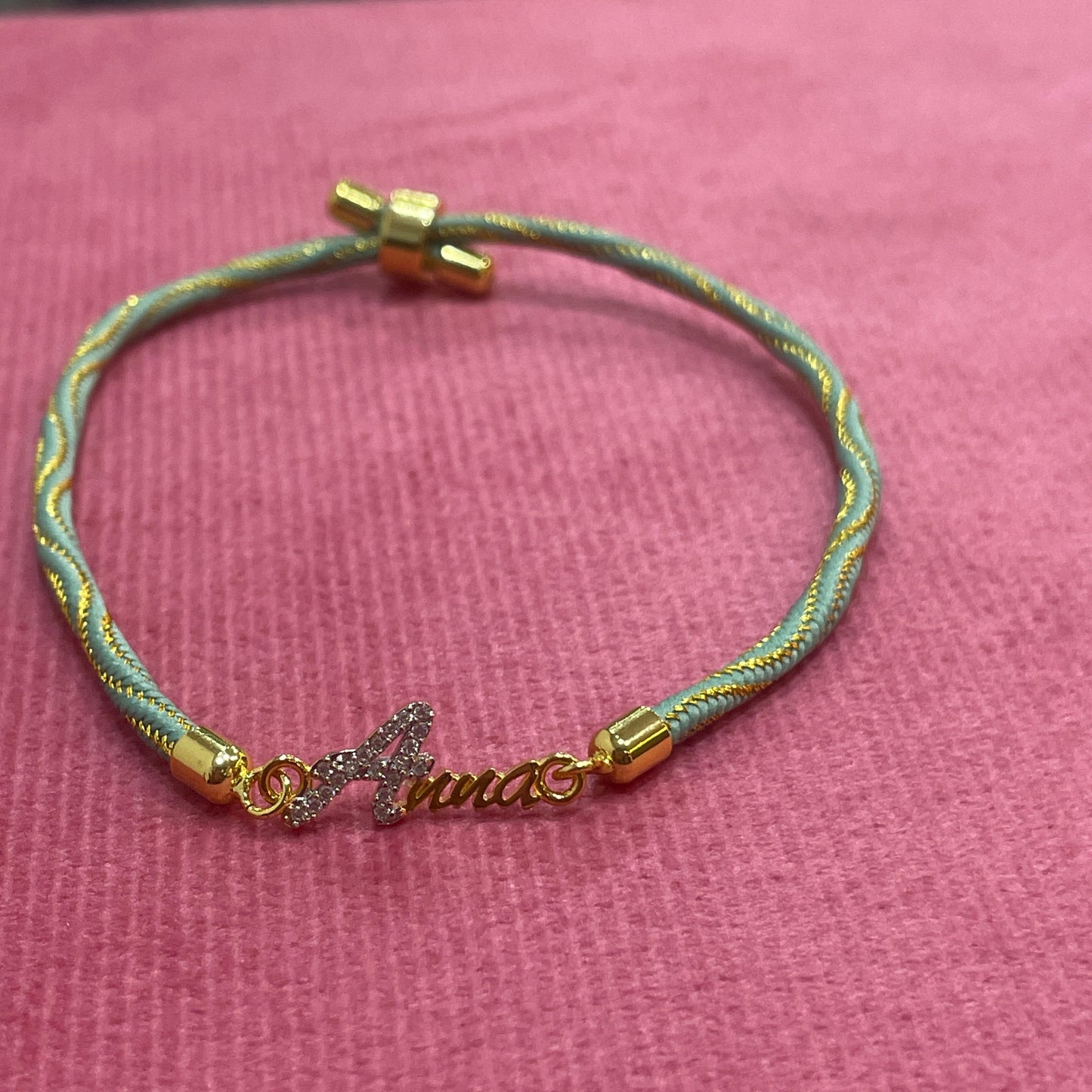 Gold-Plated Name Rakhi for Brother | CZ Script Charm on Teal & Gold Twisted Thread