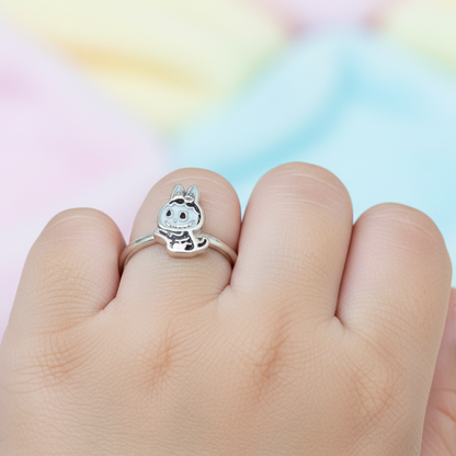Hand wearing a silver ring with a cartoon character on a colorful background