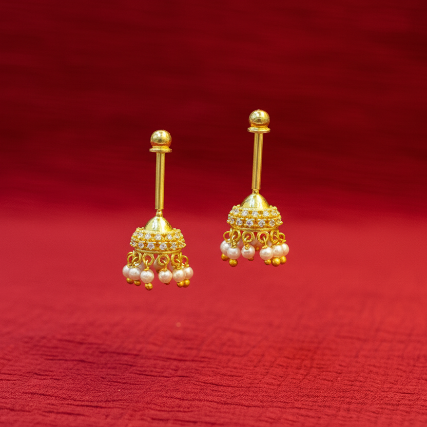 Gold earrings with pearl drops on a red fabric background