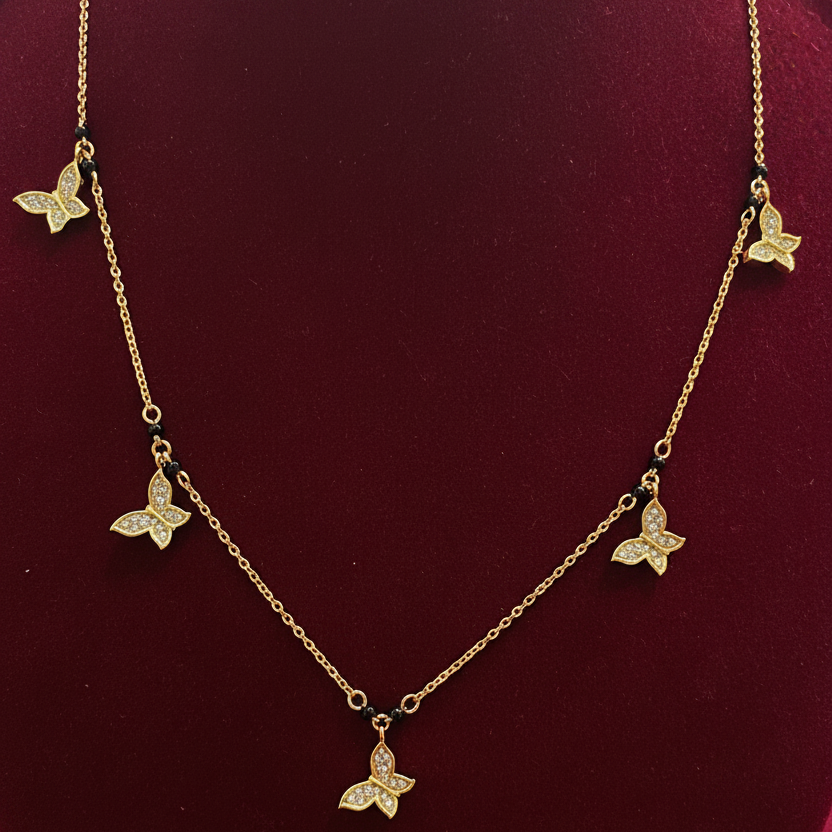 Gold butterfly necklace on a red velvet surface