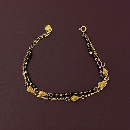Gold and black beaded bracelet on a red fabric background