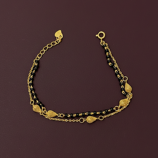 Gold and black beaded bracelet on a red fabric background