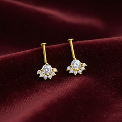 Gold earrings with clear gemstones on a burgundy fabric background