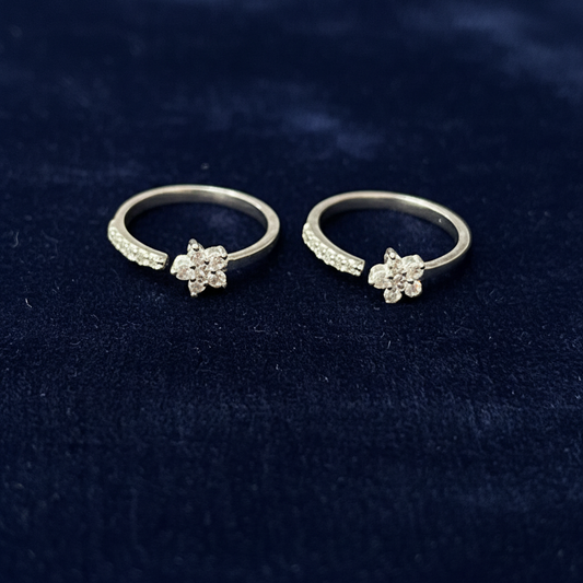Two silver rings with floral designs on a red textured fabric background