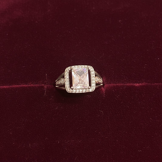 Diamond ring on a green fabric background with red fabric partially covering it