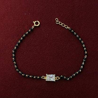 Bracelet with gold and black beads on a red background