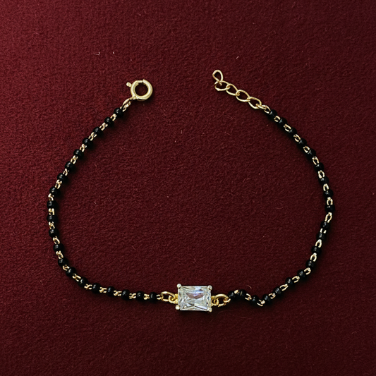 Bracelet with gold and black beads on a red background