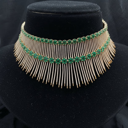 Gold and green gemstone necklace on a pink cushion