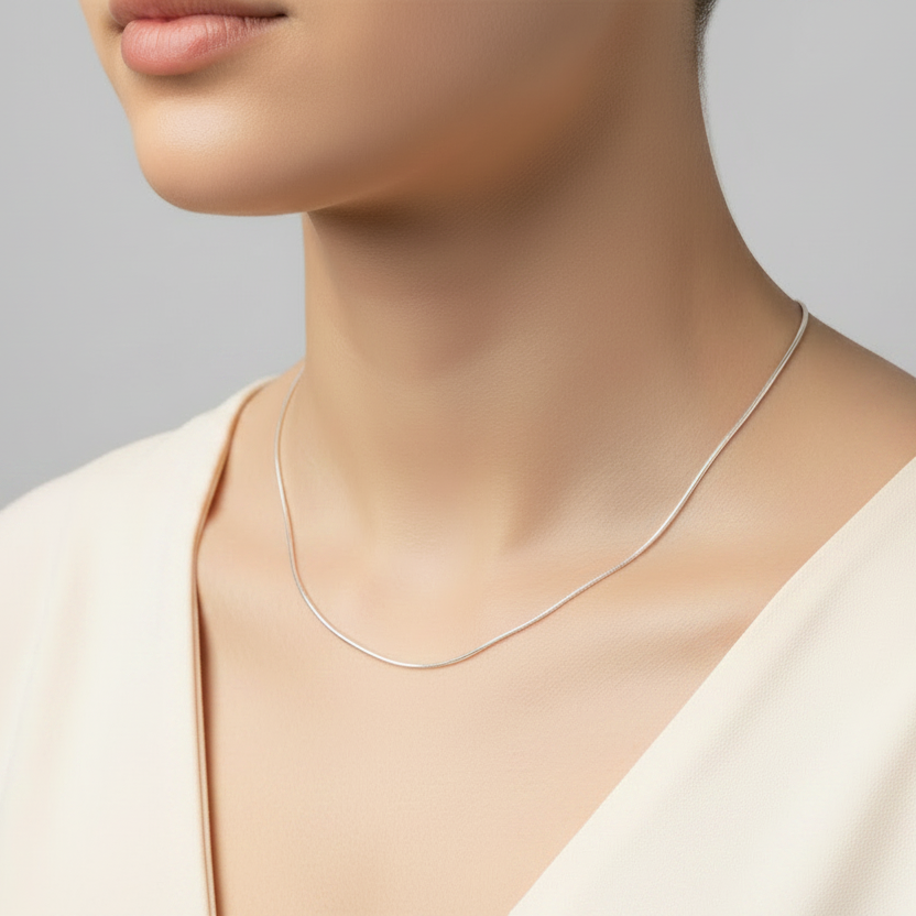 Silver necklace on a person against a gray background