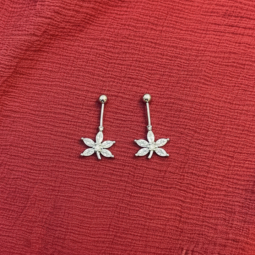 Flower-shaped earrings on a red textured fabric background