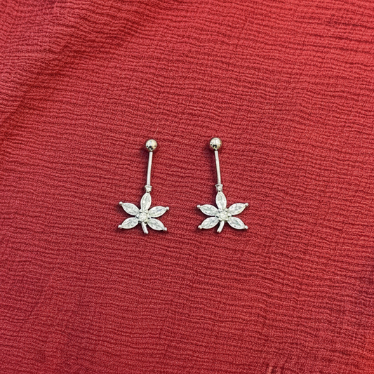 Flower-shaped earrings on a red textured fabric background
