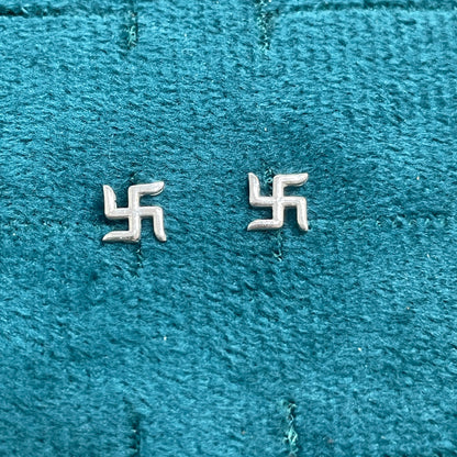 Two silver swastika symbols on a textured blue fabric background