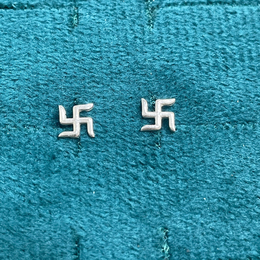 Two silver swastika symbols on a textured blue fabric background