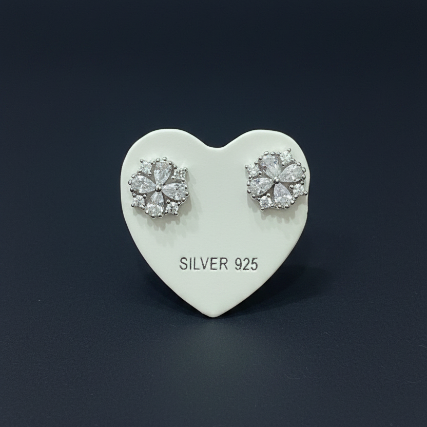Silver earrings on a heart-shaped card with 'SILVER 925' text, placed on a red fabric background.