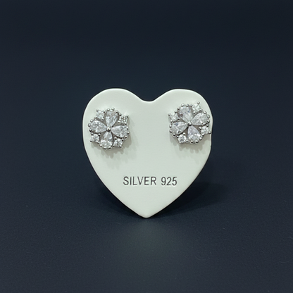 Silver earrings on a heart-shaped card with 'SILVER 925' text, placed on a red fabric background.