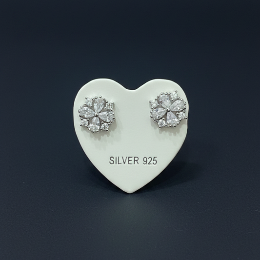 Silver earrings on a heart-shaped card with 'SILVER 925' text, placed on a red fabric background.
