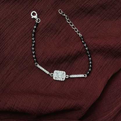 Silver bracelet with a black beaded chain on a red fabric background