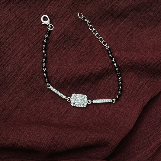 Silver bracelet with a black beaded chain on a red fabric background