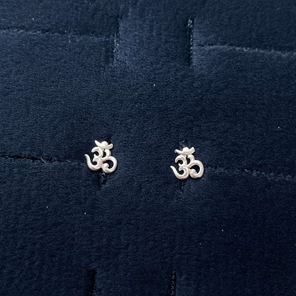Two silver floral earrings on a textured blue fabric background