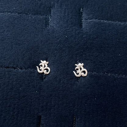 Two silver floral earrings on a textured blue fabric background