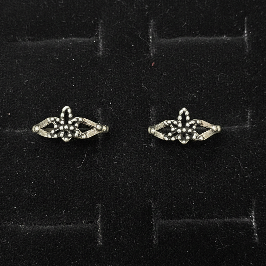 Pair of silver earrings with gemstones on a pink fabric background