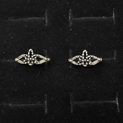 Pair of silver earrings with gemstones on a pink fabric background