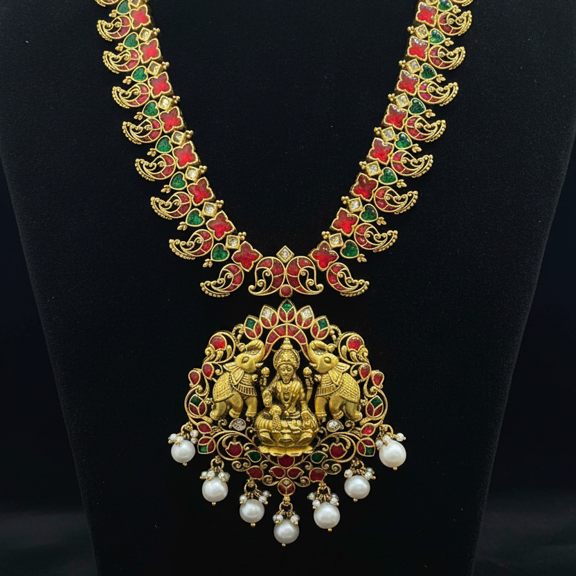 Gold necklace with green and red stones on a red fabric background
