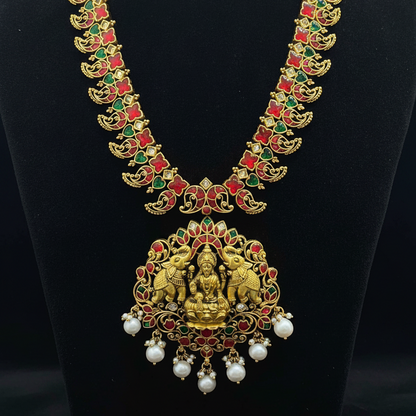 Gold necklace with green and red stones on a red fabric background