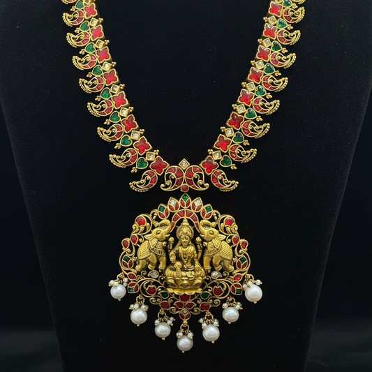 Gold necklace with green and red stones on a red fabric background