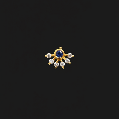 Gold ring with a blue gemstone on a person's finger against a red fabric background