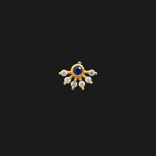 Gold ring with a blue gemstone on a person's finger against a red fabric background