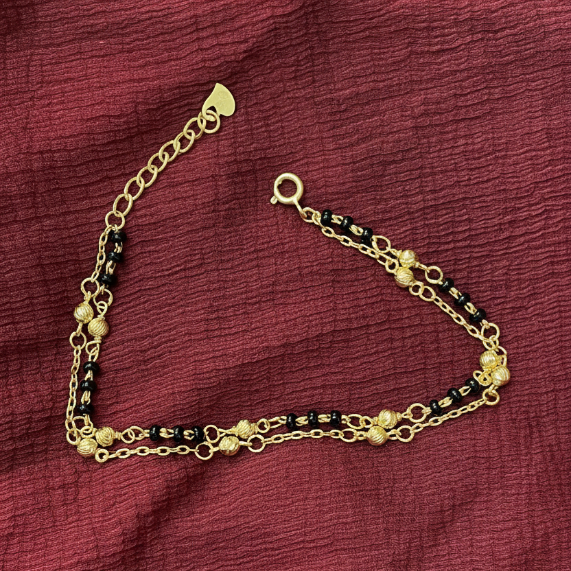 Gold bracelet with black beads on a red fabric background