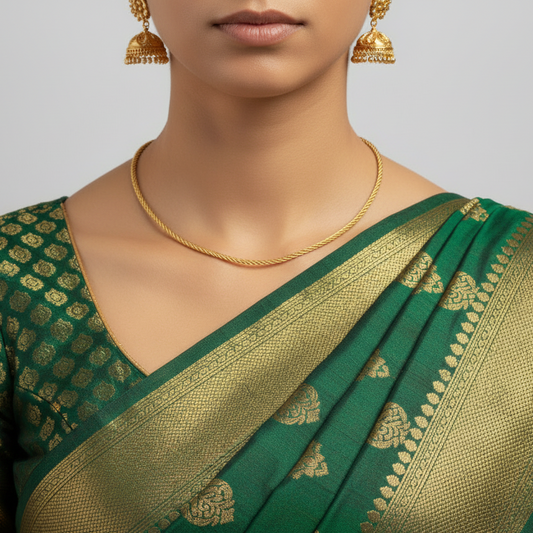 Woman wearing a green and gold saree with matching jewelry on a gray background