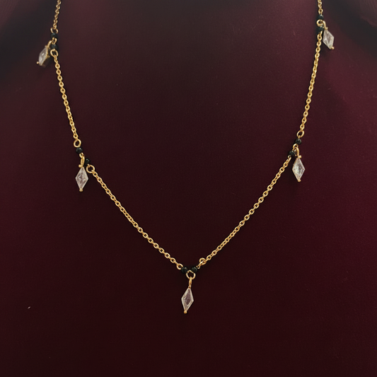 Gold necklace with small pendants on a red fabric background