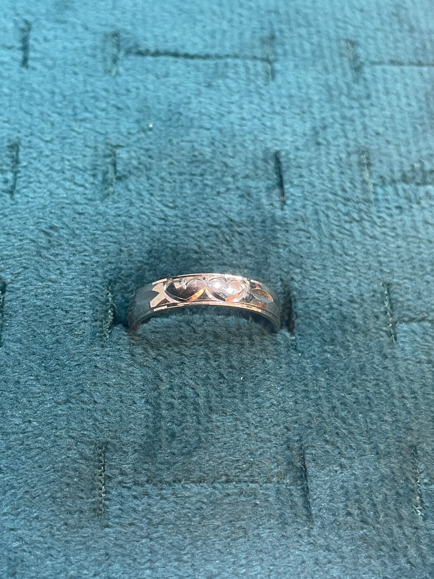 Silver ring with intricate design on a textured blue fabric background