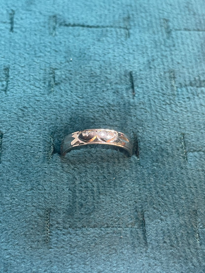 Silver ring with intricate design on a textured blue fabric background