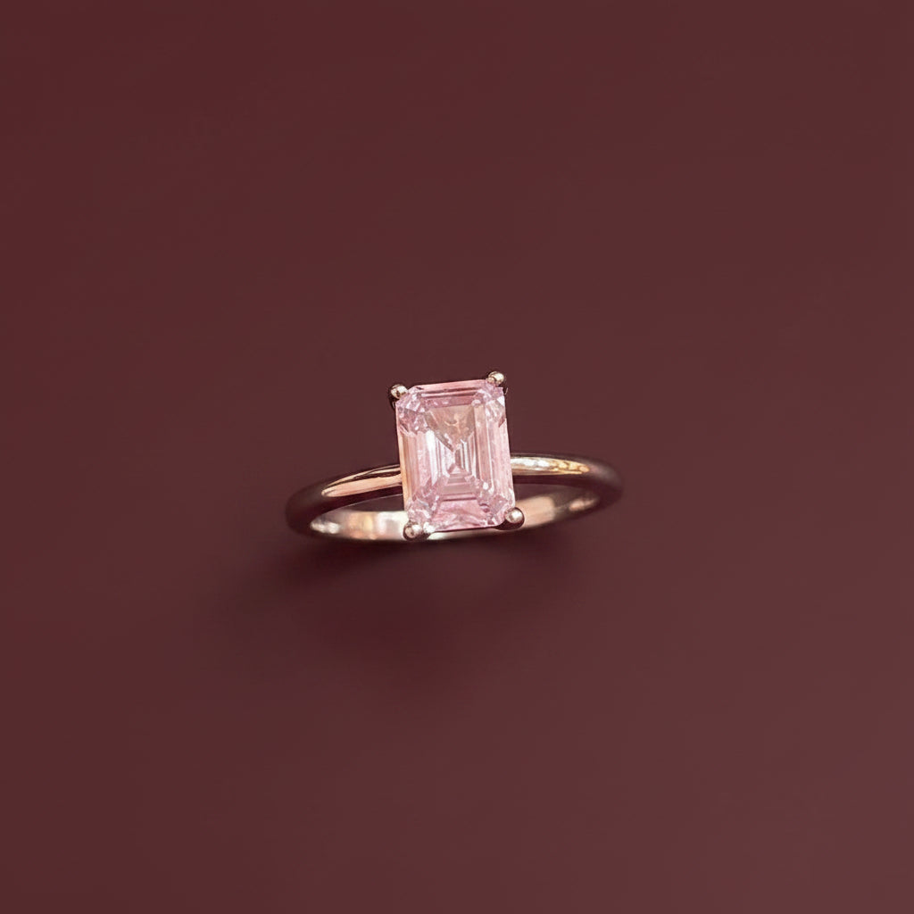 Pink ring with a rectangular gemstone on a textured surface