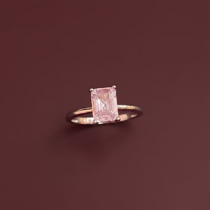 Pink ring with a rectangular gemstone on a textured surface
