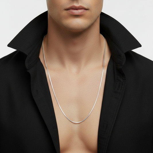 Man wearing a gray shirt with a silver chain necklace on a light gray background