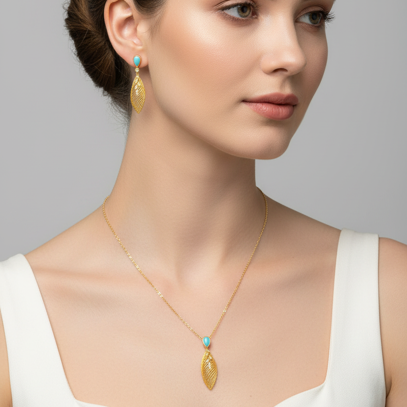 Woman wearing gold earrings and necklace against a gray background