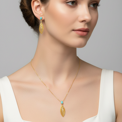 Woman wearing gold earrings and necklace against a gray background