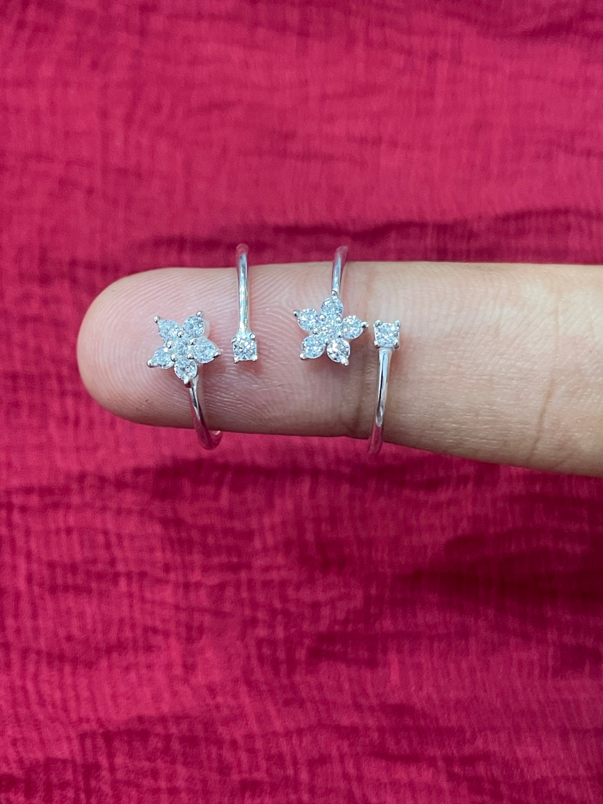 Close-up of a hand wearing two silver star-shaped rings on a red fabric background