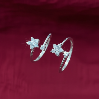 Close-up of a hand wearing two silver star-shaped rings on a red fabric background