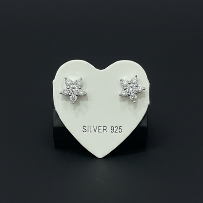 Heart-shaped silver earring on a red fabric background