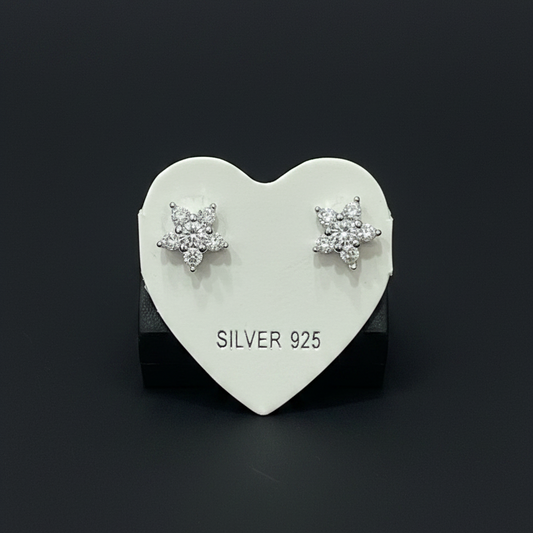 Heart-shaped silver earring on a red fabric background