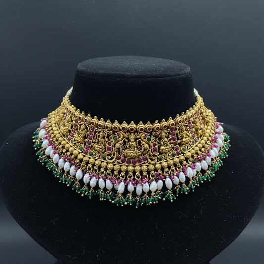 Decorative gold necklace with gemstones on a pink cushion