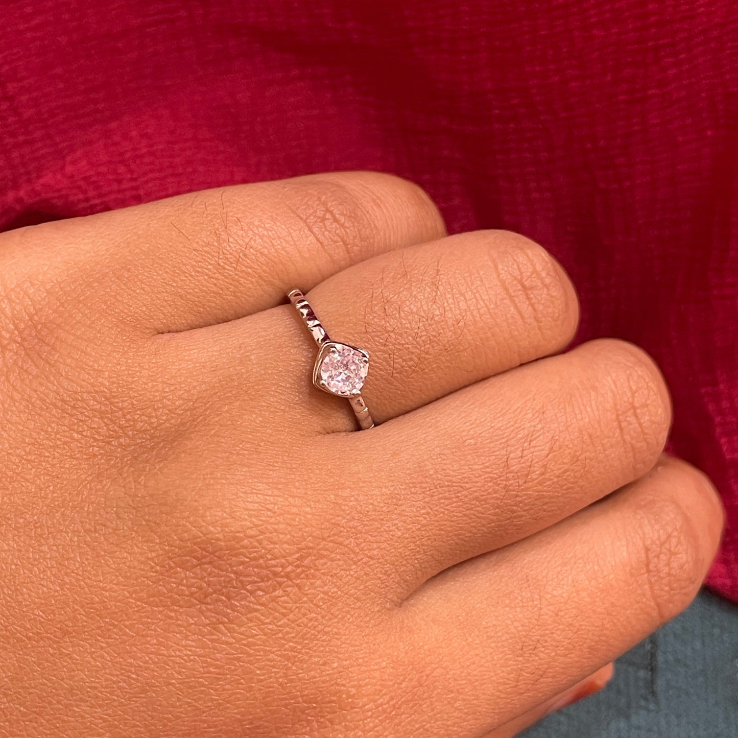 Hand wearing a diamond ring with a red and blue background