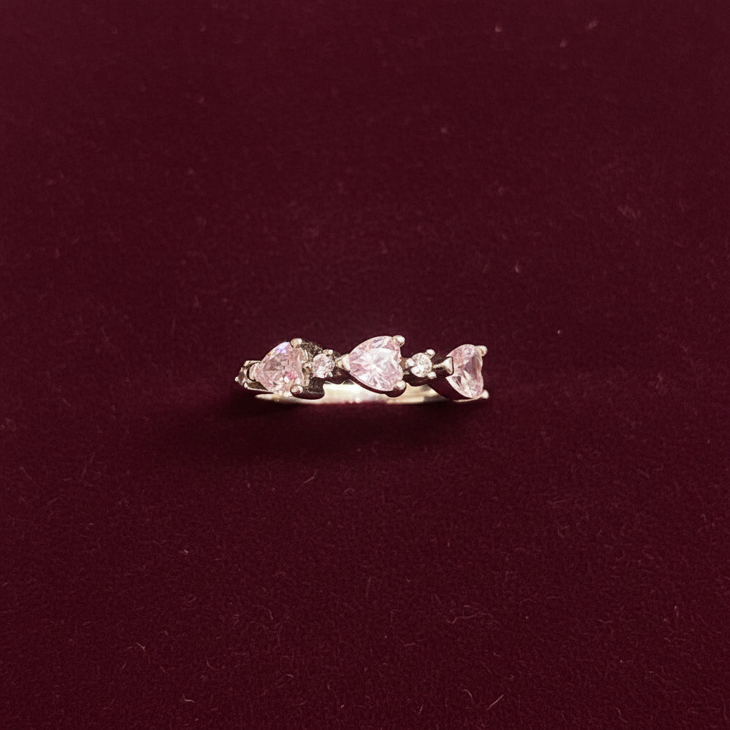 Close-up of a pink heart-shaped earring on a textured green fabric background