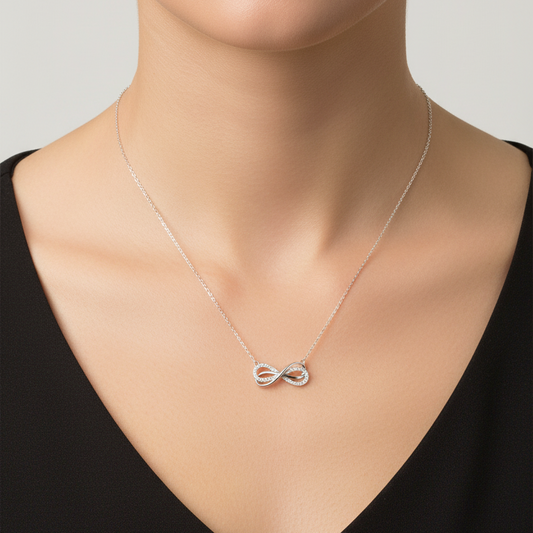 Silver necklace with a bow pendant on a gray card against a red fabric background